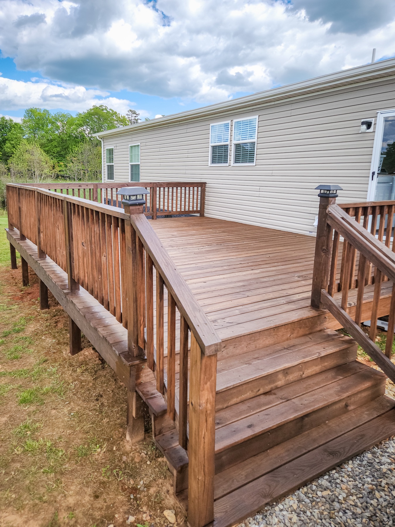 Completed brown-stained deck with stairs and railings beside a home