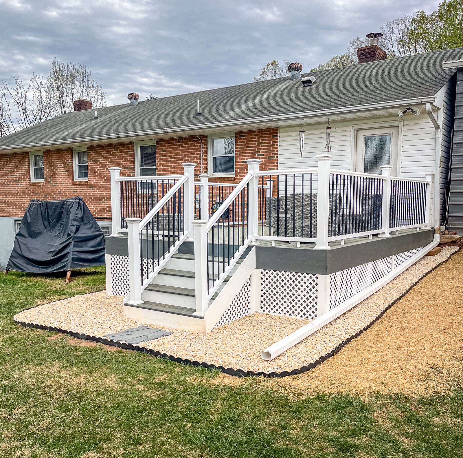 Completed gray composite deck with white railings, black balusters, stairs, and lattice skirting