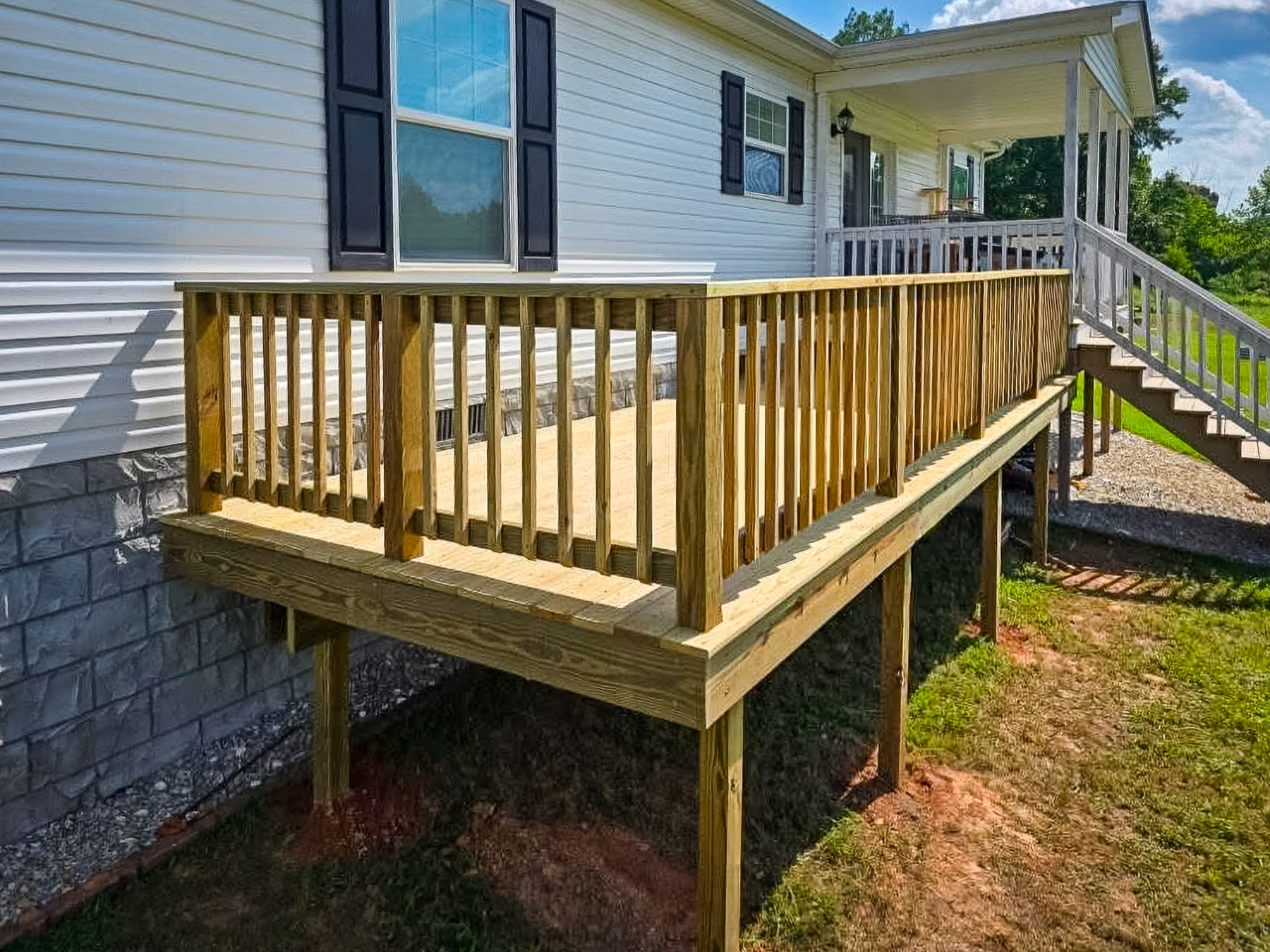 New pressure-treated wood deck and railing built alongside a home