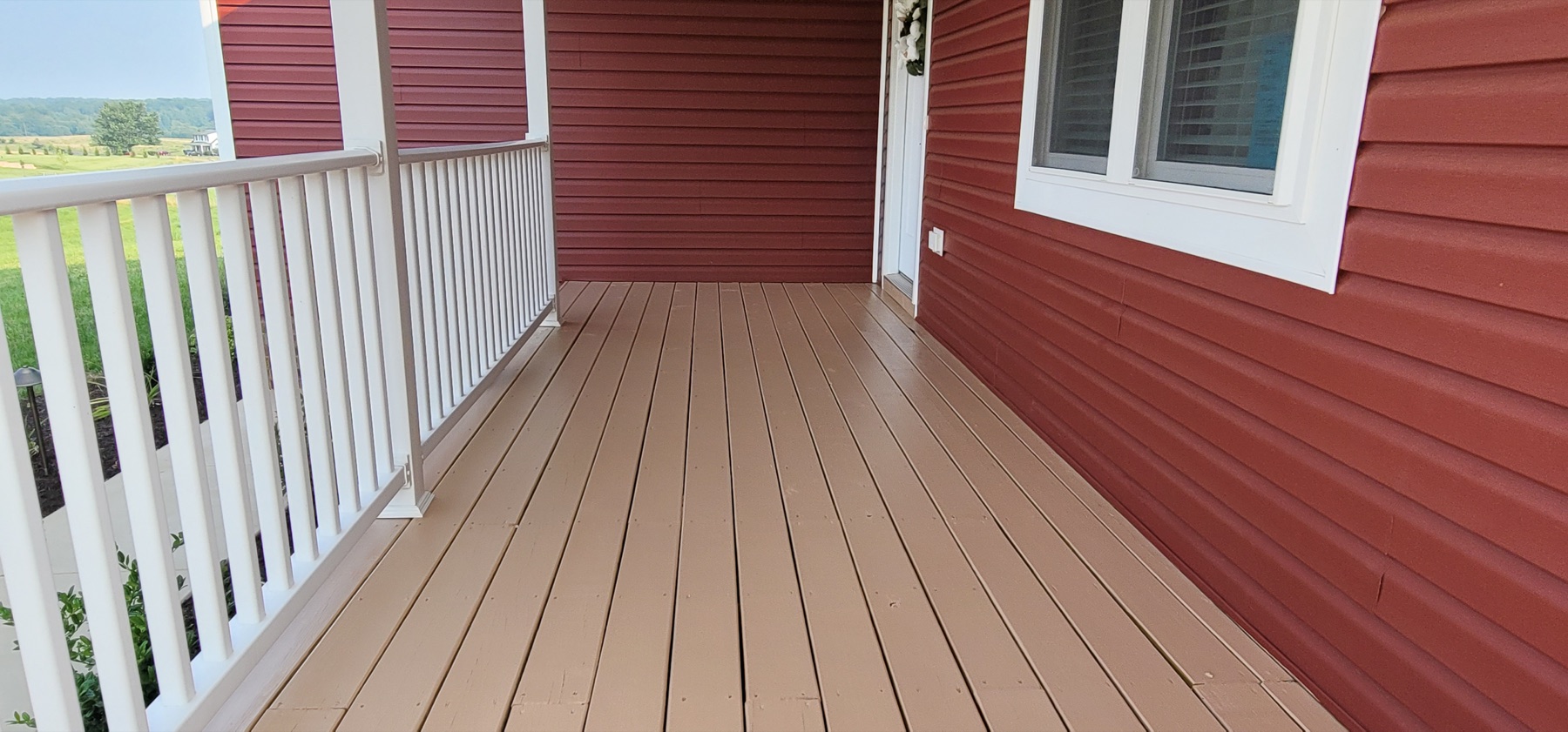 Finished red exterior siding, white porch railing, and painted porch floor